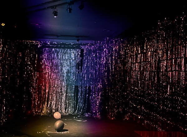 stage with a silver background and a multicolor spotlight shining on two balloons.